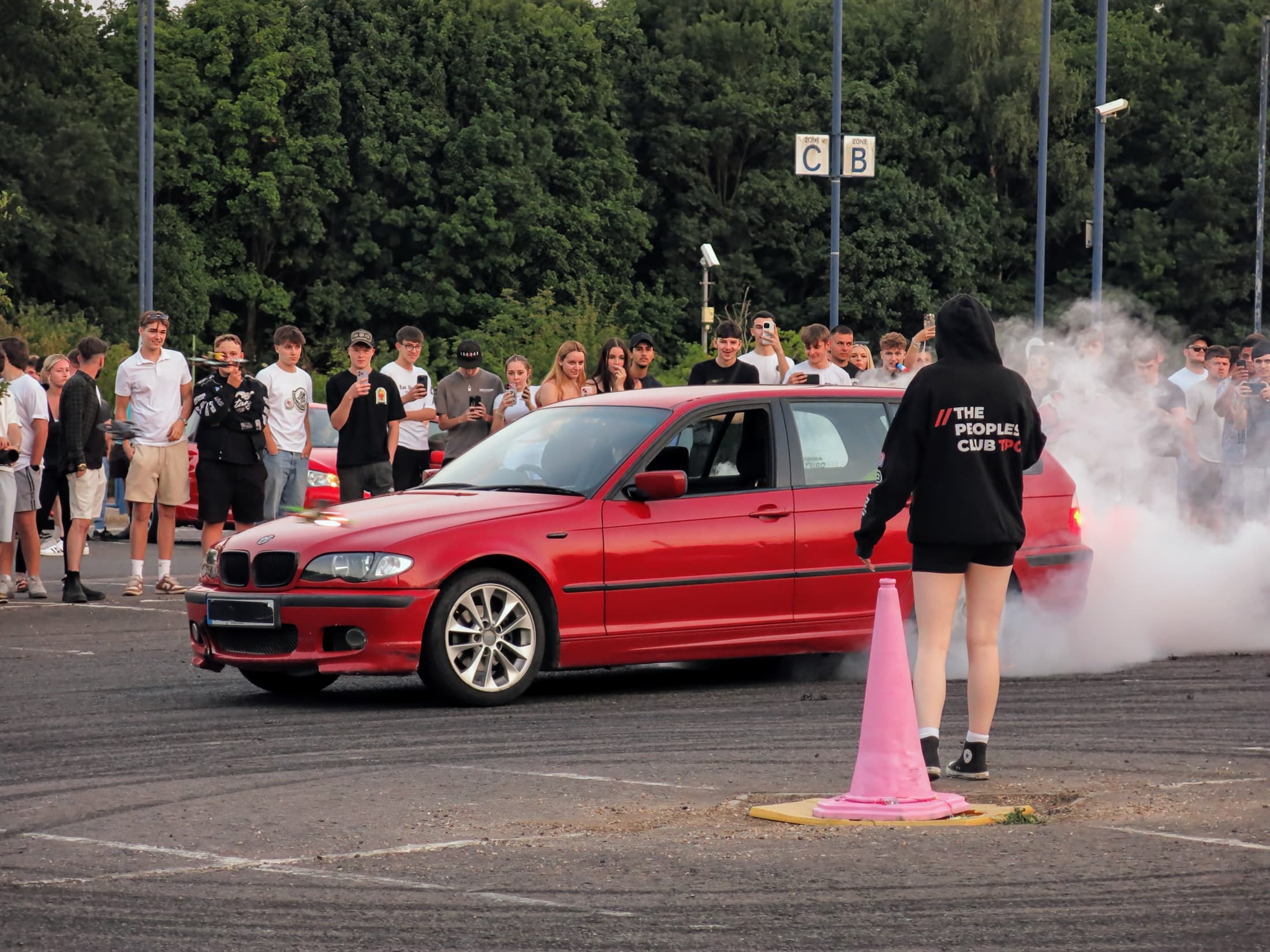 Red BMW making smoke in front of a crowd at an automotive event