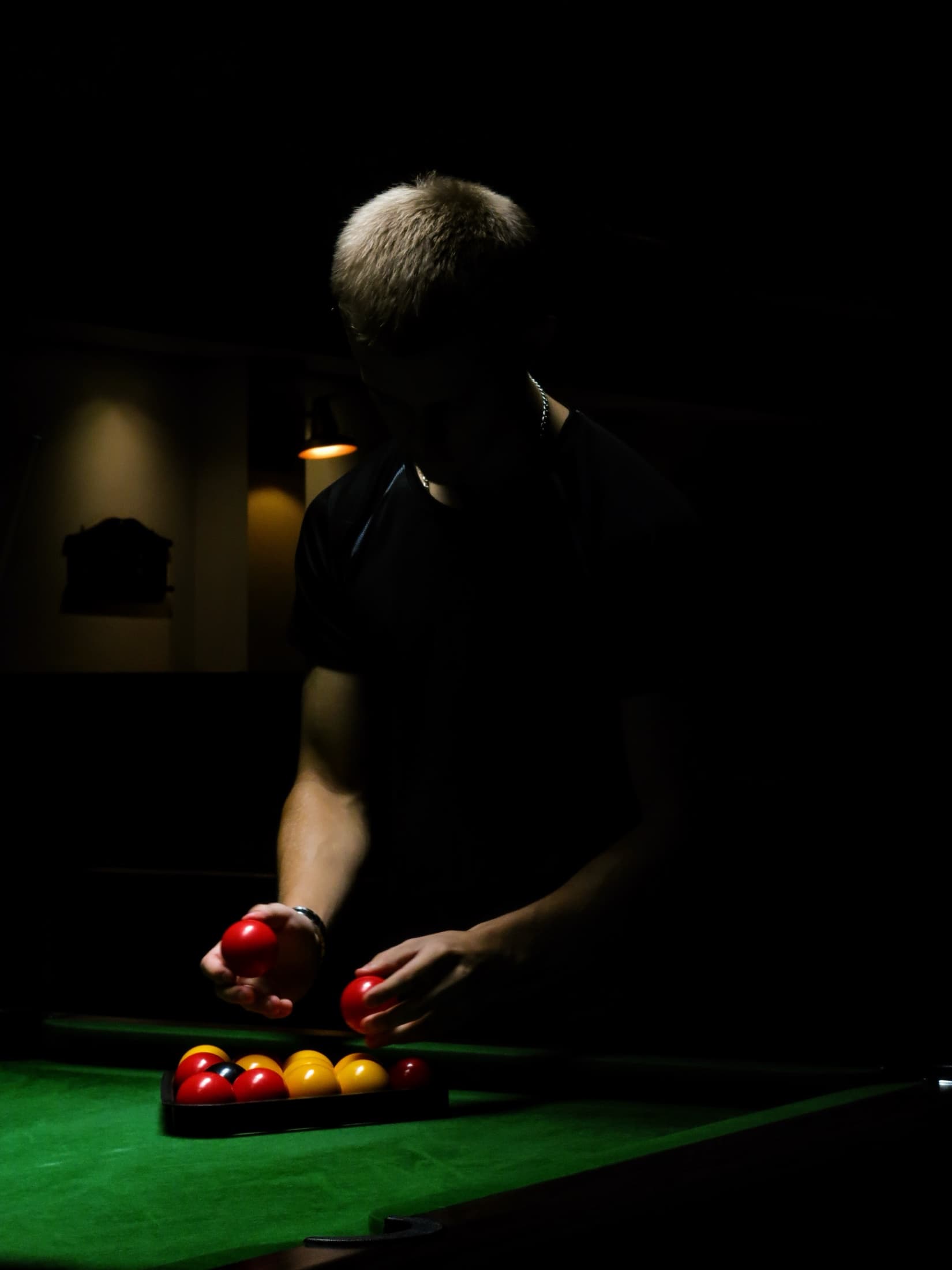 Pool player setting the balls beneath a single overhead light