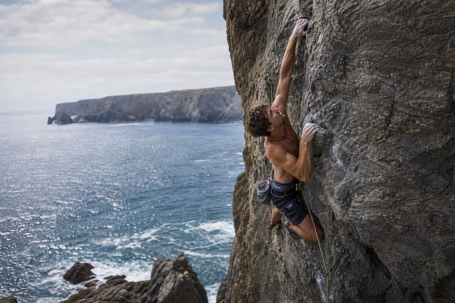 Rock climber working high on a rugged sea cliff