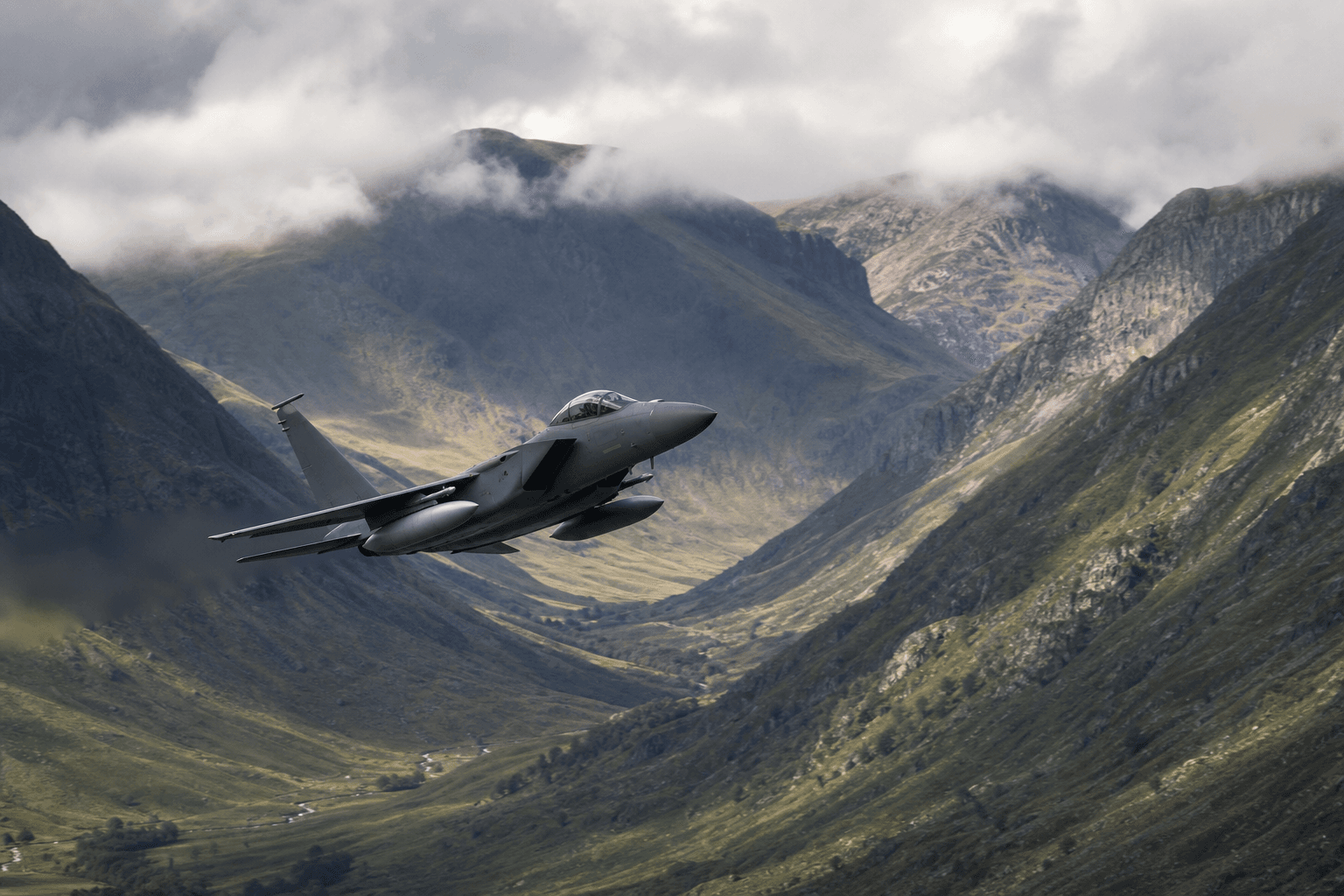 Military fast jet flying low through a dramatic mountain valley