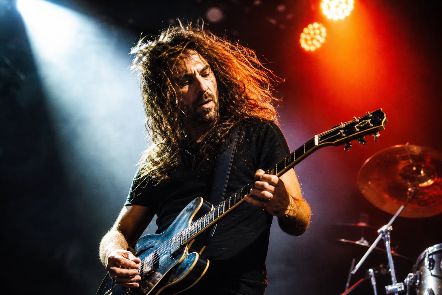 Guitarist performing intensely beneath stage lighting