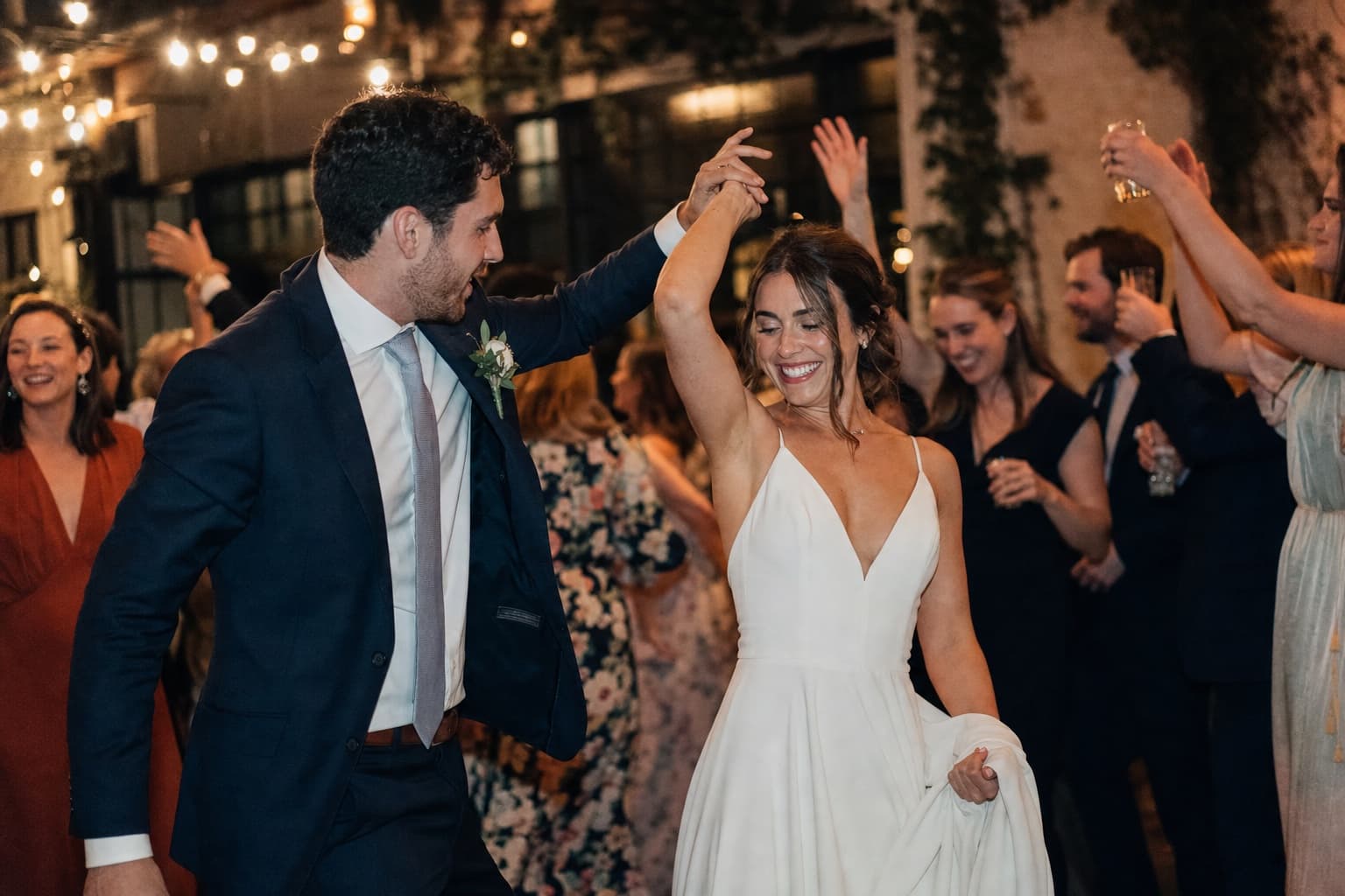 Newly married couple dancing among friends at their reception